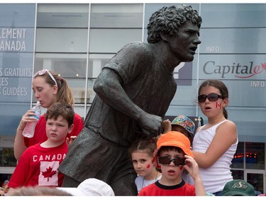 Kids use the Terry Fox statue to get a better look at what's going on as people flock to Parliament Hill and the downtown core to enjoy Canada's 147th birthday.