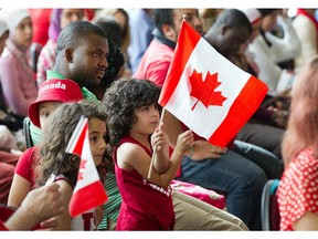 Kids wave the flag as 50 new Canadians take the Citizenship Oath during a special Canada Day ceremony held at the Canadian Museum of History in Gatineau.