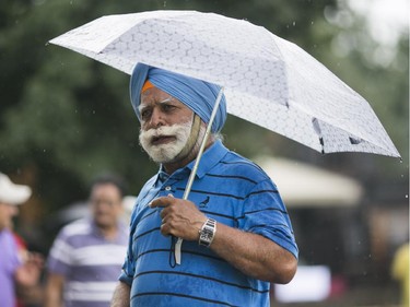 Mahan Sings shelters himself from the rain during a picnic at Saunders Farm. Hundreds of people from the Ottawa indian community took part in the India Canada Association: Unity Picnic at Saunders Farm in Munster, July 27, 2014.        (Chris Roussakis/Ottawa Citizen)