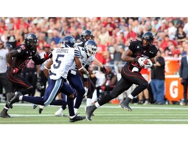 Marcus Henry of the Ottawa Redblacks runs away from the  Toronto Argonauts' defines at TD Place in Ottawa during the franchise home opener of the Redblacks on Friday, July 18, 2014.