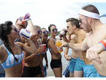 Members of "Hit Face" take part in some pre-game team hydration as they take part in the HOPE Volleyball Summerfest at Mooney's Bay Beach in Ottawa on Saturday, July 12, 2014.