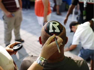 Michael Partridge has his head painted with the Redblacks logo before his team's home opener against the Toronto Argonauts at TD Place on Friday, July 18, 2014.