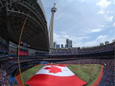 A general view of the Rogers Centre on Canada Day as a large Canadian flag is unfurled on the field during the singing of the Canadian anthem before the start of the Toronto Blue Jays MLB game against the Milwaukee Brewers on July 1, 2014 at Rogers Centre in Toronto, Ontario, Canada.