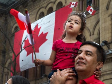 Oscar Morales holds up his daughter Oriana to get a better look at Parliament Hill as people flock to Parliament Hill and the downtown core to enjoy Canada's 147th birthday.