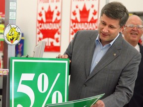 Prime Minister Stephen Harper uses a sign to show a future 1 percent cut to the Goods and Services Tax (GST) at a Giant Tiger department store, on Friday June 30, 2006. The tax cut takes effect on July 1, 2006.