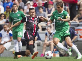 Ottawa Fury FC forward Oliver (centre) fights for the ball against New York Cosmos defenceman Carlos Mendes (right) during their NASL soccer match-up at TD Place in Ottawa, July 20, 2014.