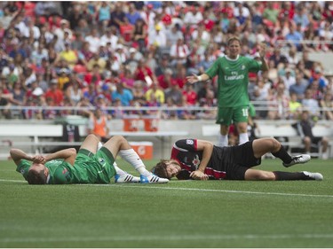 Ottawa Fury FC forward Tom Heinemann (right) and New York Cosmos defenceman Hunter Gorskie (left) lay on the pitch after colliding during their NASL soccer match-up at TD Place in Ottawa, July 20, 2014.