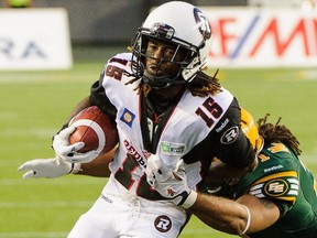 Jamill Smith runs with the ball as Edmonton's Calvin McCarty grabs him Friday night at Commonwealth Stadium in the Alberta capital.