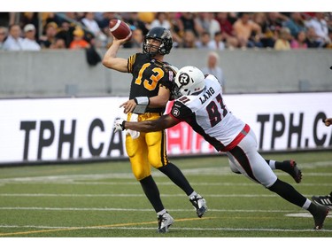 Dan LeFevour #13 of the Hamilton Tiger-Cats is hit as he throws an incomplete  pass during CFL game action by Brandon Lang #91 of the Ottawa Redblacks on July 26, 2014 at Ron Joyce Stadium in Hamilton, Ontario, Canada.