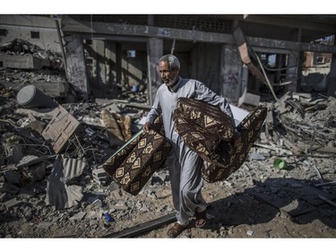 A Palestinian carries cushions he found in the rubble of destroyed buildings on July 27, 2014 in the Shejaiya residential district of Gaza City as families returned to find their homes ground into rubble by relentless Israeli tank fire and air strikes. The Islamist Hamas movement fired more rockets at Israel, despite claims it had accepted a UN request for a 24-hour extension of a humanitarian truce in war-torn Gaza.