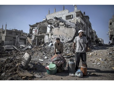 Palestinian men gather things they found in the rubble of destroyed buildings on July 27, 2014 in the Shejaiya residential district of Gaza City as families returned to find their homes ground into rubble by relentless Israeli tank fire and air strikes. The Islamist Hamas movement fired more rockets at Israel, despite claims it had accepted a UN request for a 24-hour extension of a humanitarian truce in war-torn Gaza.