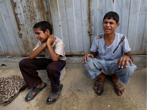 Palestinian youths weep while sitting by the rubble of a home destroyed by an Israeli strike in Khan Younis in the southern Gaza Strip, Friday, July 25, 2014. Early Friday, Israeli warplanes struck tens of houses throughout the Gaza Strip as international efforts continue to broker a cease-fire in the 18-day-old war.