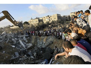 Palestinians gather around the rubble of a building where at least 20 members of the Al Najar extended family were killed by an Israeli strike in Khan Younis, in the southern Gaza Strip, Saturday, July 26, 2014. At least 20 members of an extended family, including at least 10 children, were killed by tank fire that hit a building on the edge of town, said Palestinian health official Ashraf al-Kidra. A brief cease-fire Saturday in the Gaza war between Israel and Hamas militants allowed thousands to return home to see the destruction.