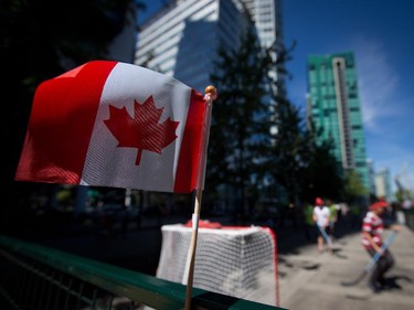 A Canadian flag is seen on a fence as people play ball hockey during Canada Day celebrations in Vancouver, B.C., on Tuesday July 1, 2014.