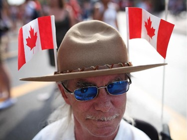 People enjoy pockets of sunshine between rain showers in downtown Ottawa during Canada Day festivities on July 1, 2014. Alex Gilris sports flags as he cruises Wellington St.