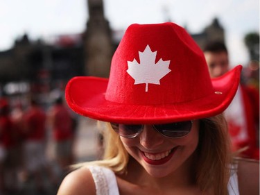 People enjoy pockets of sunshine between rain showers in downtown Ottawa during Canada Day festivities on July 1, 2014. Madison Edwards sports a colourful hat as she cruises Wellington St.