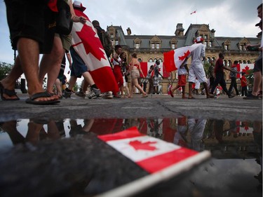 People enjoy pockets of sunshine between rain showers in downtown Ottawa during Canada Day festivities on July 1, 2014.