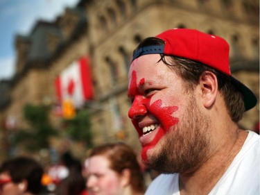 People enjoy pockets of sunshine between rain showers in downtown Ottawa during Canada Day festivities on July 1, 2014. Alex Petrant shows his true colours painted on his face.