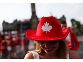 People enjoy pockets of sunshine between rain showers in downtown Ottawa during Canada Day festivities on July 1, 2014. Madison Edwards sports a colourful hat as she cruises Wellington St.