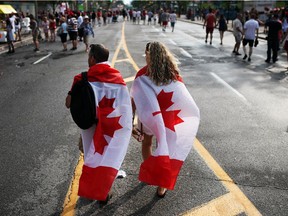 People enjoy pockets of sunshine between rain showers in downtown Ottawa during Canada Day festivities on July 1, 2014.