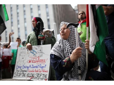 People gather at the Canadian Tribute to Human Rights memorial on Saturday, July 26, 2014 as they call for an end to the war in Gaza.