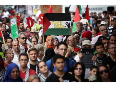 People gather at the Canadian Tribute to Human Rights memorial on Saturday, July 26, 2014 as they call for an end to the war in Gaza.