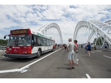 People look on as a OC Transpo bus carrying VIPs including Steve Desroches, councillor for Gloucester - South Nepean, is the first vehicle to rolls across the Strandherd-Armstrong Bridge after its grand opening in Ottawa on Saturday, July 12, 2014. The bridge connects the communities of Barrhaven and Riverside South over the Rideau River.