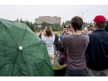 People look on as the Sir John Carling building demolished in Ottawa on Sunday, July 13, 2014. The former headquarters of Agriculture and Agri-Food Canada at 930 Carling, completed in 1967, is being demolished at a cost of $4.8 million.