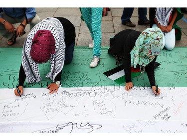 People march sign the Palestinian Flag as it lays on Parliament Hill on Saturday, July 26, 2014 as they call for an end to the war in Gaza.