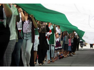 People march with the Palestinian Flag on Saturday, July 26, 2014 as they call for an end to the war in Gaza.