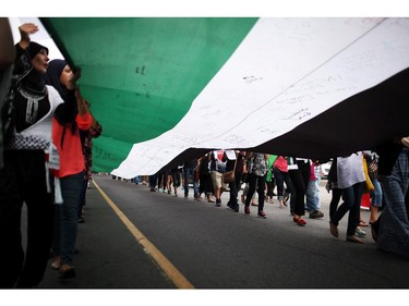 People march with the Palestinian Flag on Saturday, July 26, 2014 as they call for an end to the war in Gaza.