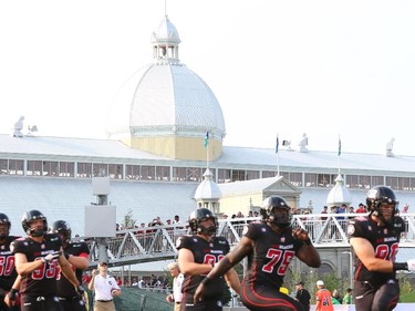 Players warm up with Aberdeen Pavillion in the background prior to the franchise opener of the Ottawa Redblacks against the Toronto Argonauts at TD Place on Friday,, July 18, 2014.