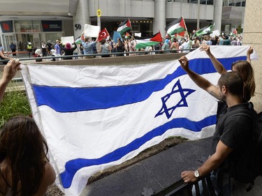 Pro-Israel counter-protesters hold the Israeli flag as pro-Palestinian supporters rally outside the Israeli Embassy in Ottawa in support of Palestinians in Gaza on Tuesday, July 22, 2014.