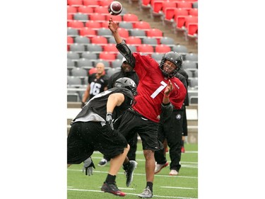QB Henry Burris hurls a ball over some incoming "linemen" during a mock march up the field as the Ottawa Redblacks practice through a downpour Tuesday morning at TD Place Stadium at Lansdowne Park.