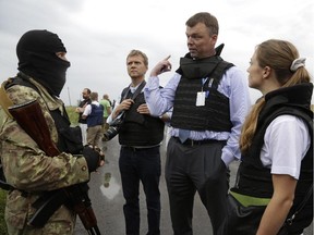 Representatives from the Organization for Security and Cooperation speak to a pro-Russia fighter at the crash site of a Malaysia Airlines jet near the village of Hrabove, Friday, July 18, 2014. R