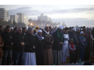 Muslim men pray at Seapoint Promenade, a popular public area next to the sea, before trying to sight the new moon, which will signify the end of the Muslim holy month of fasting, called Ramadan, on July 27, 2014, in the centre of Cape Town. Muslims around the world celebrated Eid al Fitr which marks the end of the month of Ramadan, after the sighting of the new moon.