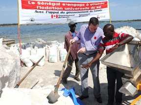 Canadian International Development and Francophonie Minister Christian Paradis (C) visits on November 11, 2013 a cooperative producing salt on the shores of Lake Rose in Dakar.