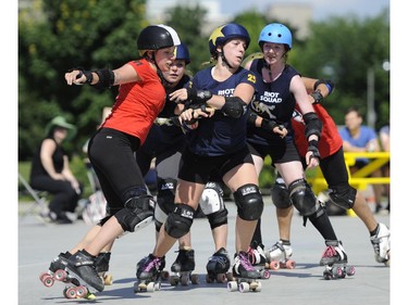 Slaughter Daughters' AustinTatious, left, challenges Riot Squad jammer BLackeyE, centre, during the Rideau Valley Roller Girls' Roller Derby Expo at the Rink of Dreams at Ottawa City Hall's Marion Dewar Plaza in Ottawa on Saturday, July 12, 2014.