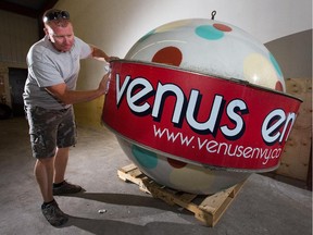 Steve Cousineau of Ambassador Realty cleans the dirt off a rare type of sign called a Norge Ball which was used as the "Venus Envy" sign on Lisgar St, but was taken down and saved during the demolition of the building last week. The owner Arthur Loeb is hoping to find a new home for it. Assignment #117712 Photo taken at 14:26 on July 15, 2014. (Wayne Cuddington/Ottawa Citizen)