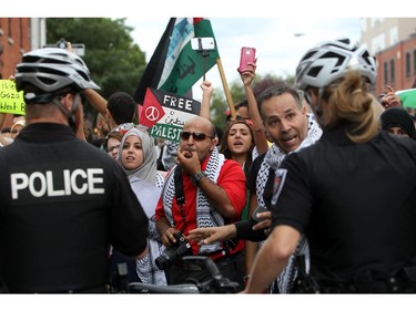 Tension mounts as a couple wearing Israeli flags pass by people marching with the Palestinian Flag and signs on Saturday, July 26, 2014, calling for an end to the war in Gaza.