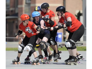 The Slaughter Daughters, in red, take on their league mates Riot Squad during the Rideau Valley Roller Girls' Roller Derby Expo at the Rink of Dreams at Ottawa City Hall's Marion Dewar Plaza in Ottawa on Saturday, July 12, 2014.