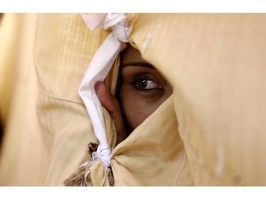 A Palestinian woman looks on through a hole in a sheet which covers her improvised tent on July 27, 2014 in the garden of Al-Shifa hospital in Gaza City, where Palestinian displaced families who have fled their homes took refugee. Hamas belatedly said it has agreed to a 24-hour humanitarian truce, shortly after Israel announced a resumption of hostilities in Gaza following a day-long pause.