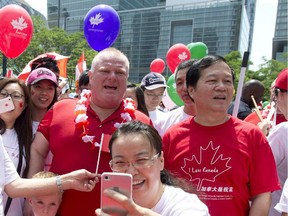 Toronto Mayor Rob Ford sings "Oh Canada" while people take photos of him shortly before marching in the National Congress of Chinese Canadians' Canada Day parade in Toronto, Ontario on Tuesday, July 1, 2014.