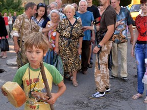 A young boy holds a loaf of bread as residents of the eastern Ukrainian city of Lysychansk queue to receive bread distributed as part of humanitarian aid on July  27, 2014.