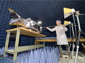 0707 asteroid satellites: A technician puts some of the finishing touches on NEOSSat at the David Florida Laboratory in Ottawa before the satellite was sent to India for launch in 2013.