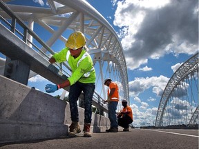 Workers finish up last minute touches as the long awaited official opening of the Strandherd-Armstrong Bridge, connecting the communities of Barrhaven and Riverside South over the Rideau River, is set to take place on Saturday, July 12, 2014.