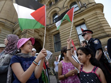 Youngers wave the Palestinian flag as they protest in front of the Langevin Block in support of Palestinians in Gaza in Ottawa on Tuesday, July 22, 2014.