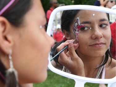 Zoe Guzman touches up her paint as people flock to Parliament Hill and the downtown core to enjoy Canada's 147th birthday.
