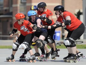 The Slaughter Daughters, in red, take on their league mates Riot Squad during the Rideau Valley Roller Girls' Roller Derby Expo at the Rink of Dreams at Ottawa City Hall's Marion Dewar Plaza in Ottawa on Saturday, July 12, 2014.