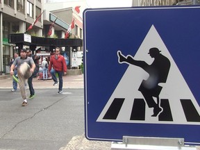 Pedestrians practice their silly walks as they cross Metcalfe Street along Sparks Street Mall Aug. 14. The mall authority has installed signs to encourage people to do their best silly walks in the spirit of John Cleese of Monty Python. (Darren Brown/Ottawa Citizen)